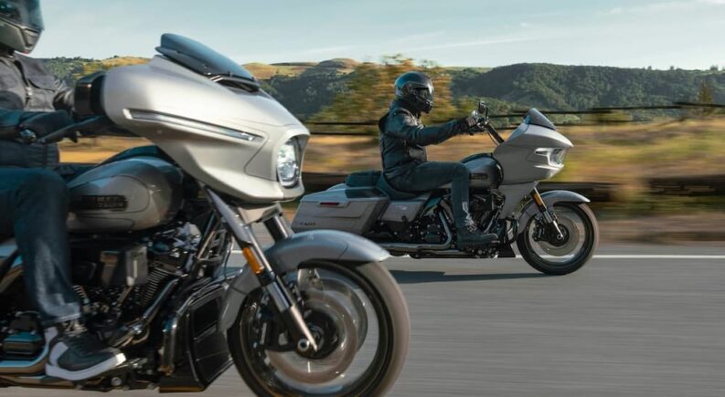 Two silver 2023 Harley-Davidson CVOs are shown riding the best motorcycle trips in the US for your fall ride.