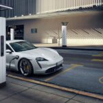 A white 2023 Porsche Taycan is shown charging after viewing electric vehicles for sale.