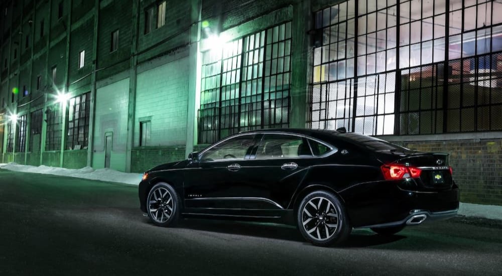 A black 2018 Chevy Impala Midnight Edition is shown parked near factory windows.