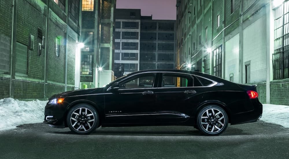 A black 2018 Chevy Impala Midnight Edition is shown parked near several city buildings.