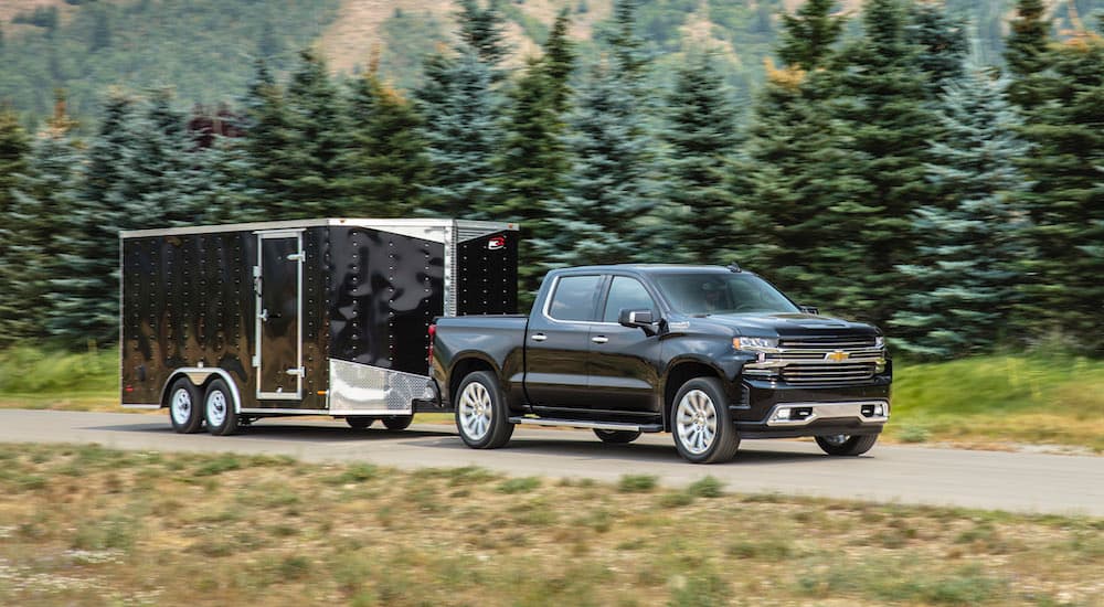 A black 2020 Chevy Silverado High Country is shown towing a trailer.