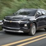 One of the most common used Chevy SUVs for sale, a black 2021 Chevy Blazer, is shown driving through a forest road.