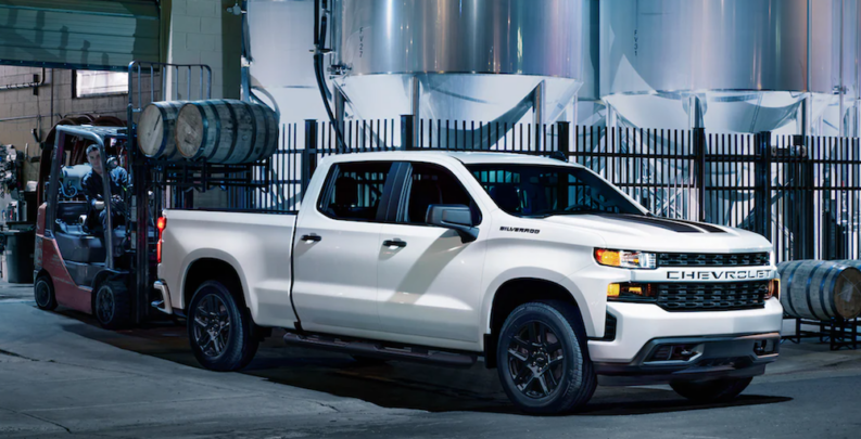 One of the more popular used trucks for sale, a white 2021 GMC Sierra, is shown parked in a factory garage.