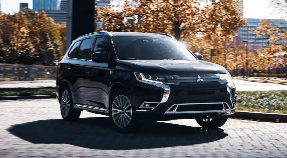 A black 2022 Mitsubishi Outlander PHEV is shown driving on a city street.