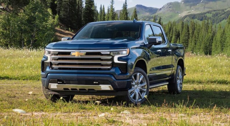 A blue 2023 Chevy Silverado 1500 High Country is shown parked on grass.