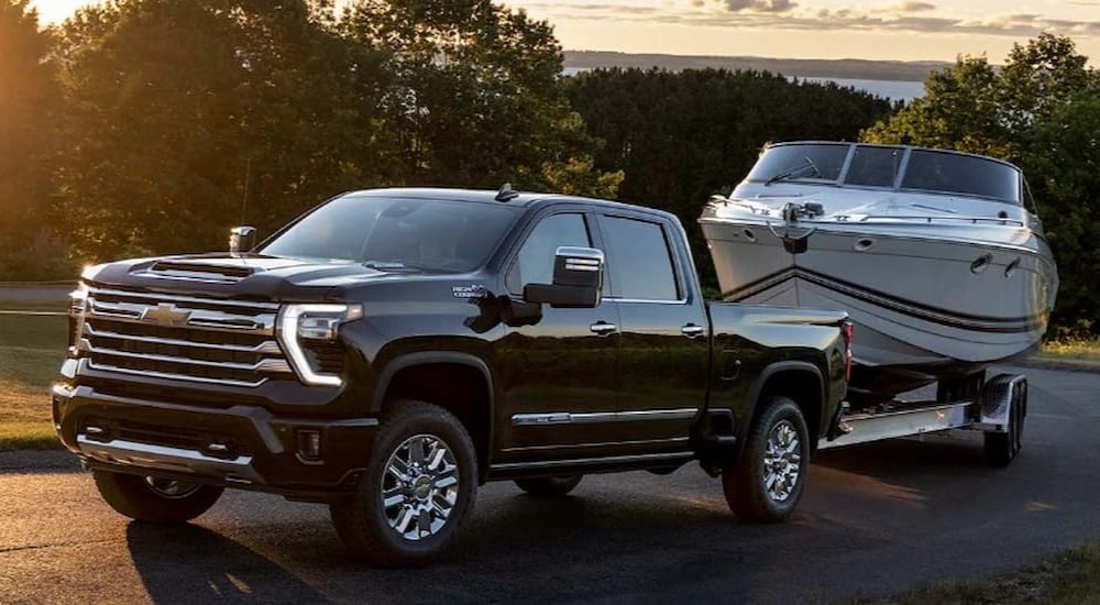 A black 2023 Chevy Silverado 1500 High Country is shown towing a boat.