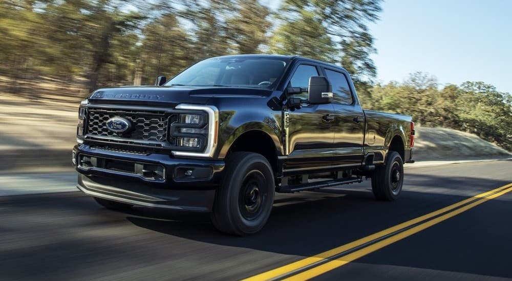 A black 2023 Ford F-250 XL-STX is shown driving on a highway.