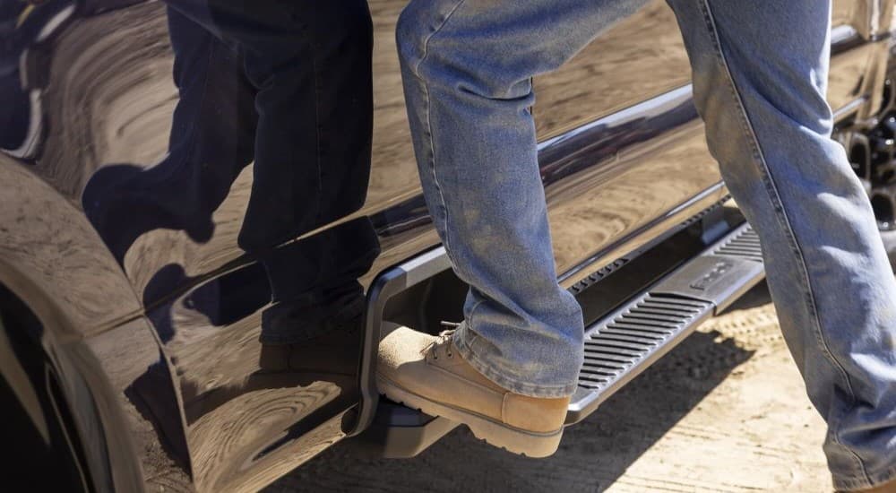 A close-up is shown of a person stepping on the foot step of a black 2023 Ford F-250 XL STX.