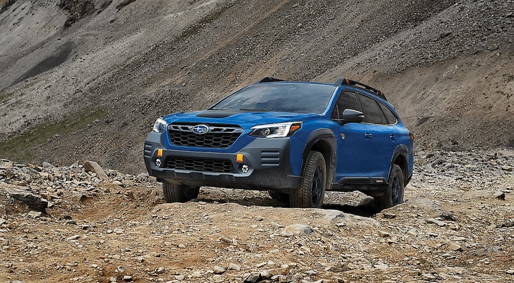 A blue 2023 Subaru Outback Wilderness is shown driving off-road in a desert.