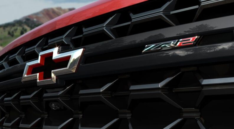 A close-up on the grille of the latest Chevy Silverado 2500 for sale, a red 2024 Chevy Silverado 2500HD ZR2, is shown.