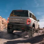 A gray 2024 Ford Bronco Sport Badlands is shown driving up a rocky desert incline.