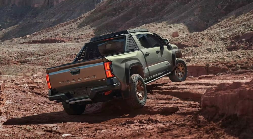 A green 2024 Toyota Tacoma is shown rock climbing off-road.