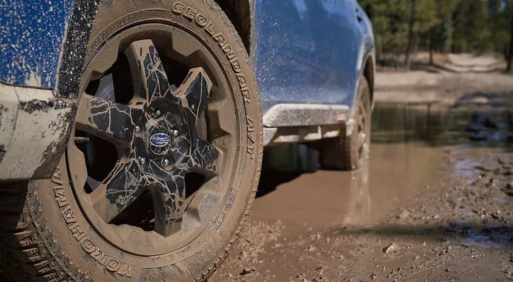 A close-up of the 2023 Subaru Outback Wilderness' tires being covered in mud is shown.