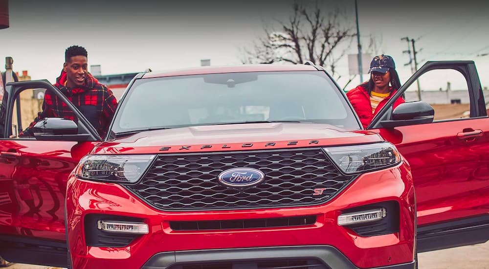 Two people are shown exiting a red 2022 Ford Explorer ST.