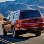 A red 2023 Wagoneer is shown driving down a desert road.