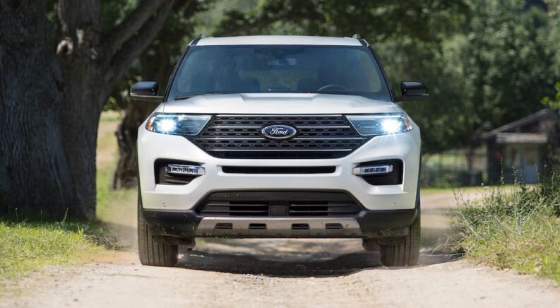One of the most popular Ford explorers for sale, a white 2023 Ford Explorer ST is shown driving in a forest.