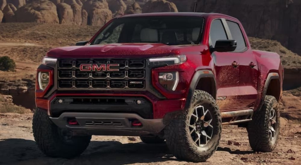 A red 2023 GMC Canyon Denali is shown parked off-road.