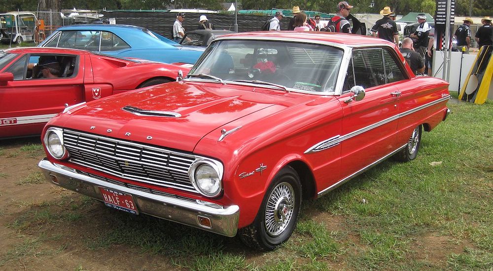 A red 1963 Ford Falcon is shown parked at a dealer.