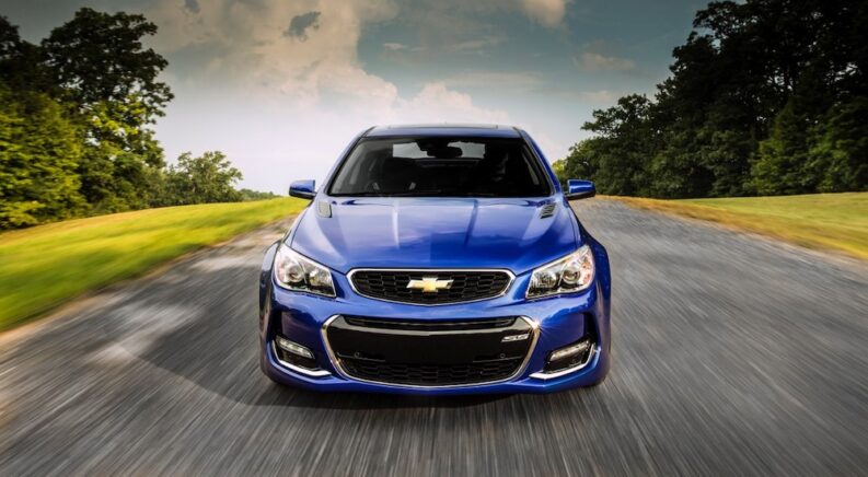 A blue 2016 Chevrolet SS is shown driving from a used Chevy dealership.