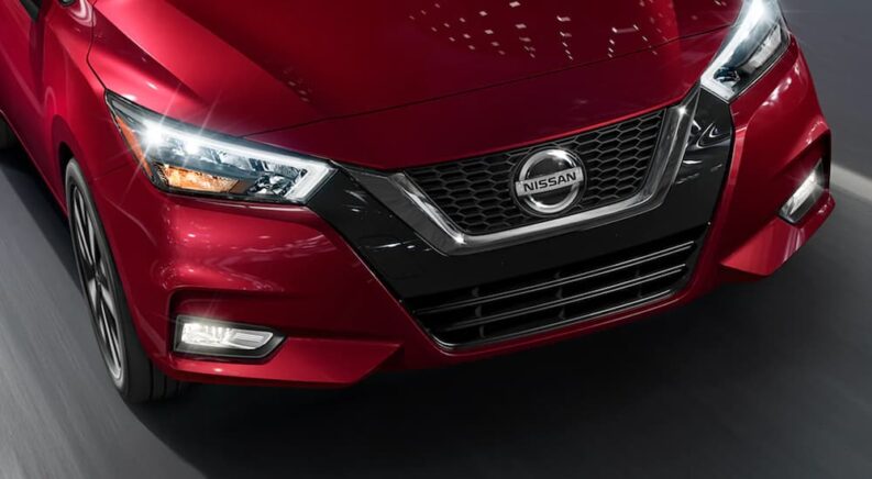 A close-up on the hood of a red 2021 Nissan Versa parked at a used Nissan dealer is shown.