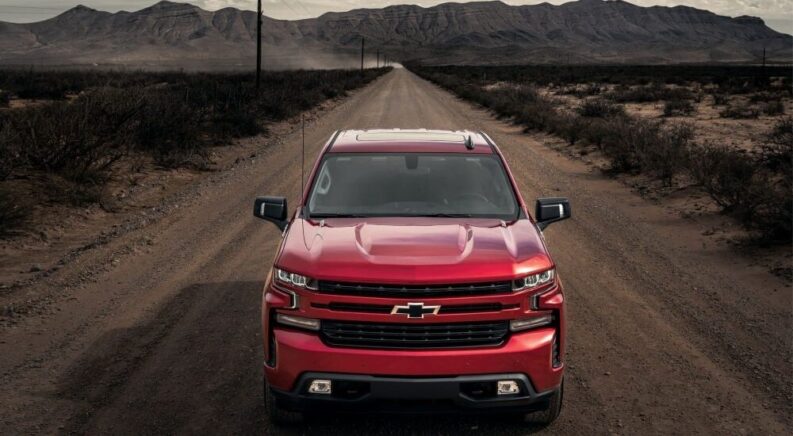 A model of Chevy Silverado for sale, the red 2023 Chevy Silverado 1500 RST, is shown driving.