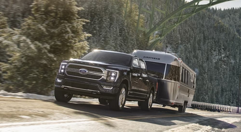 A black 2023 Ford F-150 Lariat is shown towing an Airstream trailer.
