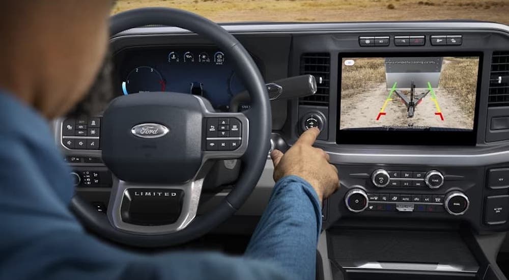 A man is shown interacting with the dashboard while backing up in a 2023 Ford F-350.