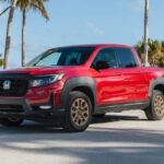 A red 2023 Honda Ridgeline HPD is shown parked near a sandy beach.