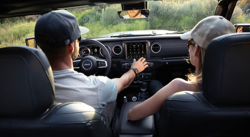 Two people are shown sitting inside of a 2023 Jeep Wrangler.
