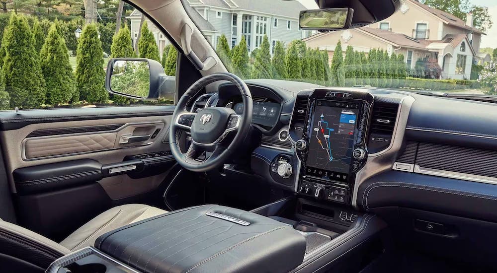 The black and brown interior of a 2023 Ram 1500 is shown, including the dashboard interface and wheel.