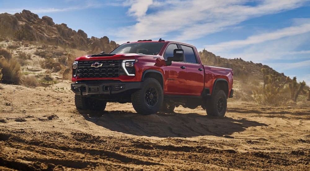 A red 2024 Chevy Silverado 1500 HD ZR2 Bison is shown parked on a mound of dirt.
