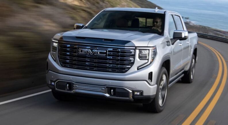 A silver 2024 GMC Sierra 1500 is shown driving on a highway after visiting a GMC dealer.