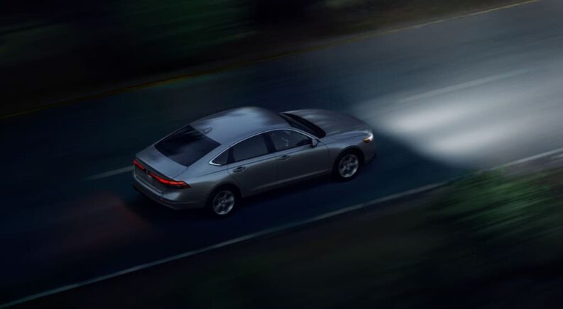 A silver 2024 Honda Accord LX is shown driving at night with headlights on.