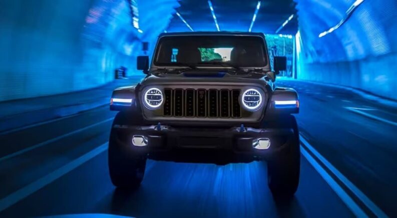 A silver 2024 Jeep Wrangler 4xe is shown driving in a tunnel after viewing EVs for sale.