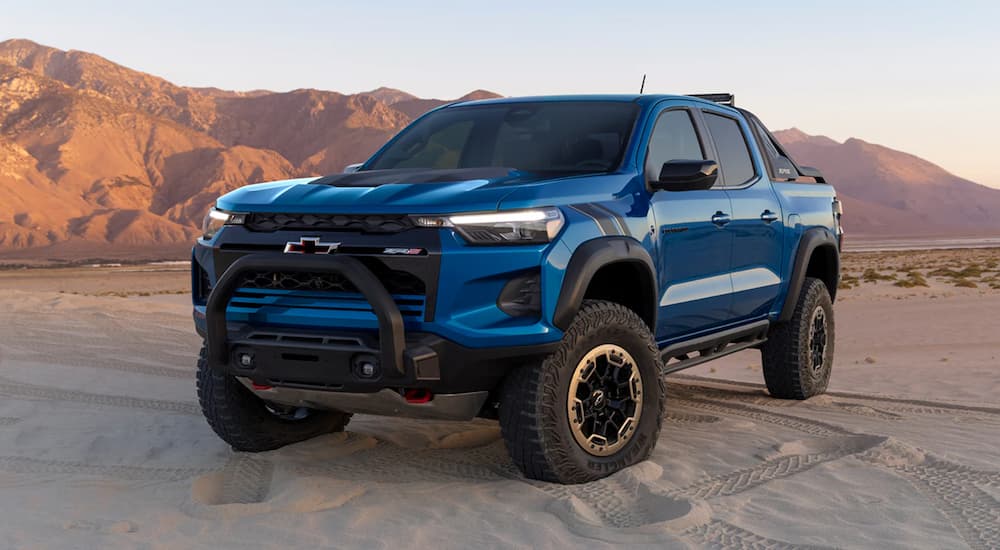 A blue 2023 Chevy Colorado ZR2 is shown parked on a sandy desert area.