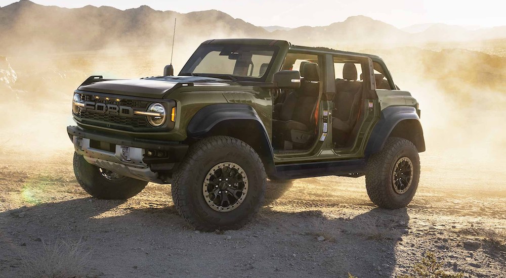 A green 2024 Ford Bronco Raptor is shown parked in a desert from the side.