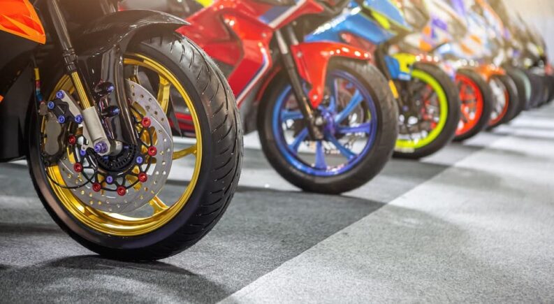 The colorful front wheels of several rare motorcycles are shown in a row.