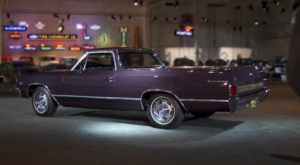 A purple 1967 Chevrolet El Camino is shown parked near neon signs.