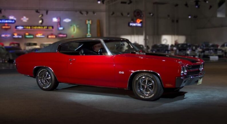 A red 1970 Chevrolet Chevelle is shown parked near a Chevy dealer.