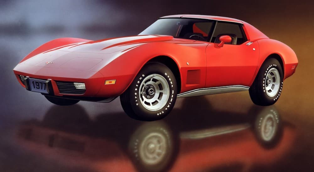 A red 1977 Chevrolet Corvette is shown parked on a shiny floor.