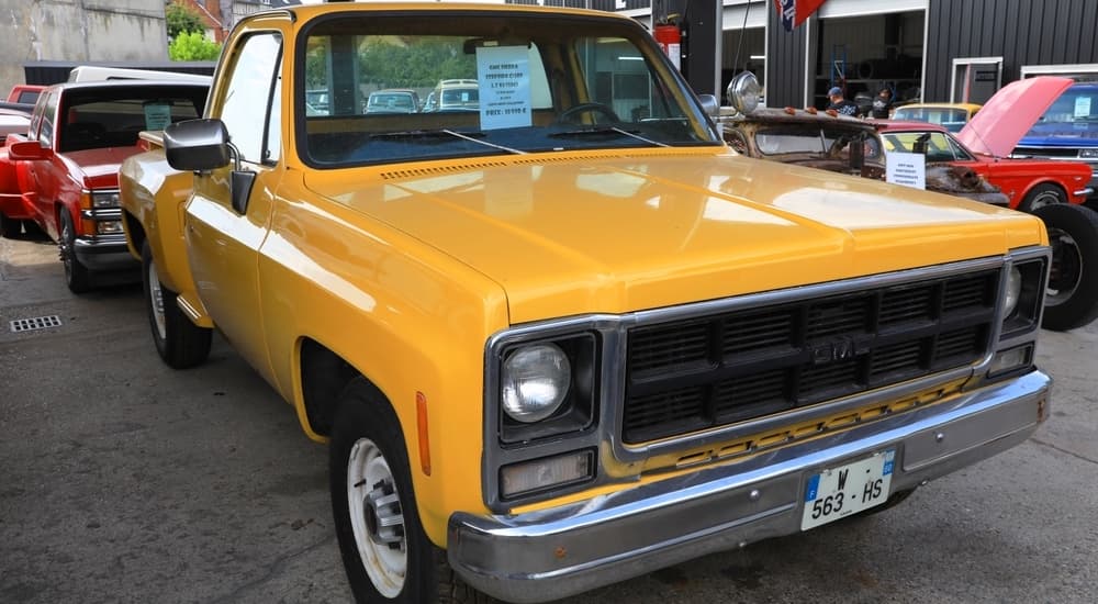 A yellow 1979 GMC Sierra Stepside C2500 is shown parked at a car show.