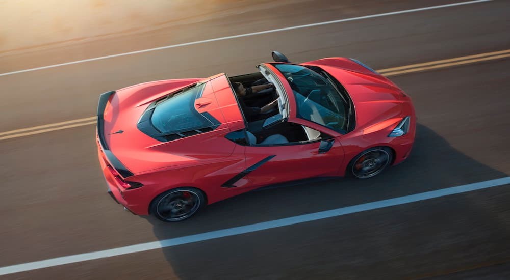 A red 202 Chevy Corvette Stingray is shown driving on a highway.