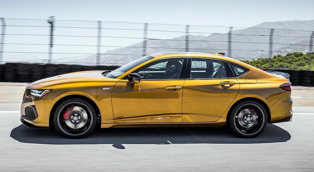 A gold 2023 Acura TLX Type S is shown driving on a racetrack.