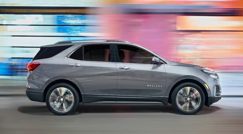 A silver 2023 Chevy Equinox LT is shown driving to a Chevy dealer.