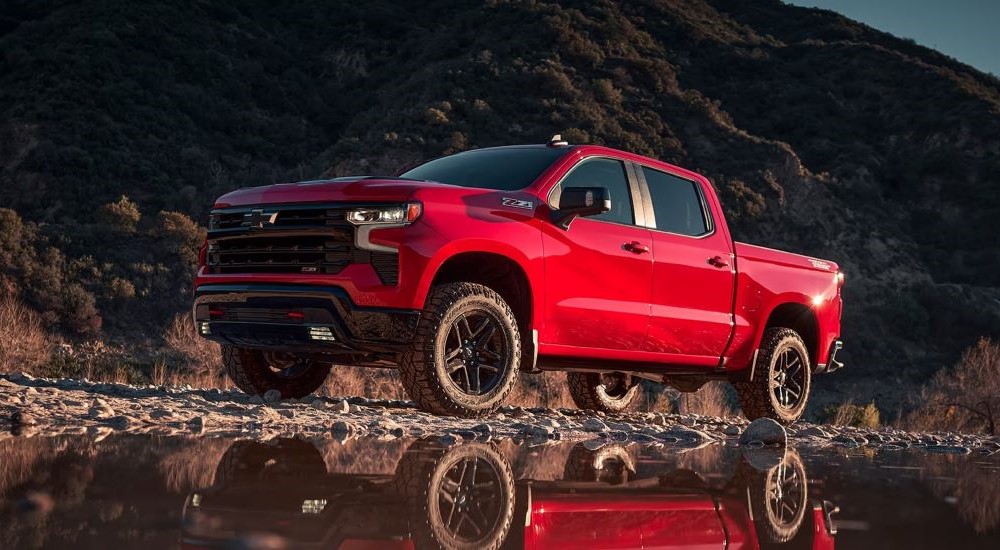 A red 2023 Chevy Silverado 1500 Z71 LT Trail Boss is shown parked near water.