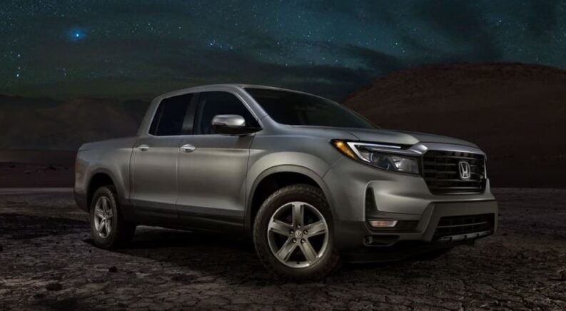 A grey 2023 Honda Ridgeline RTL-E is shown parked off-road at night.