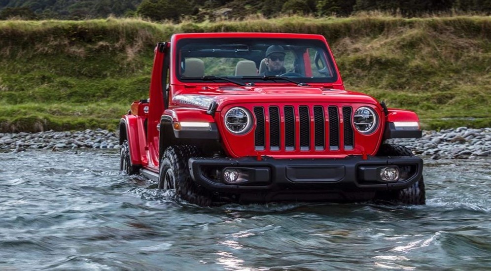 A red 2023 Jeep Wrangler Rubicon is shown driving off-road.