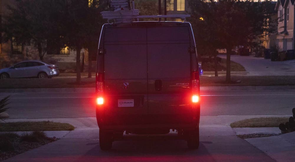A black 2023 Ram ProMaster is shown from behind with its brake lights glowing in the dark.