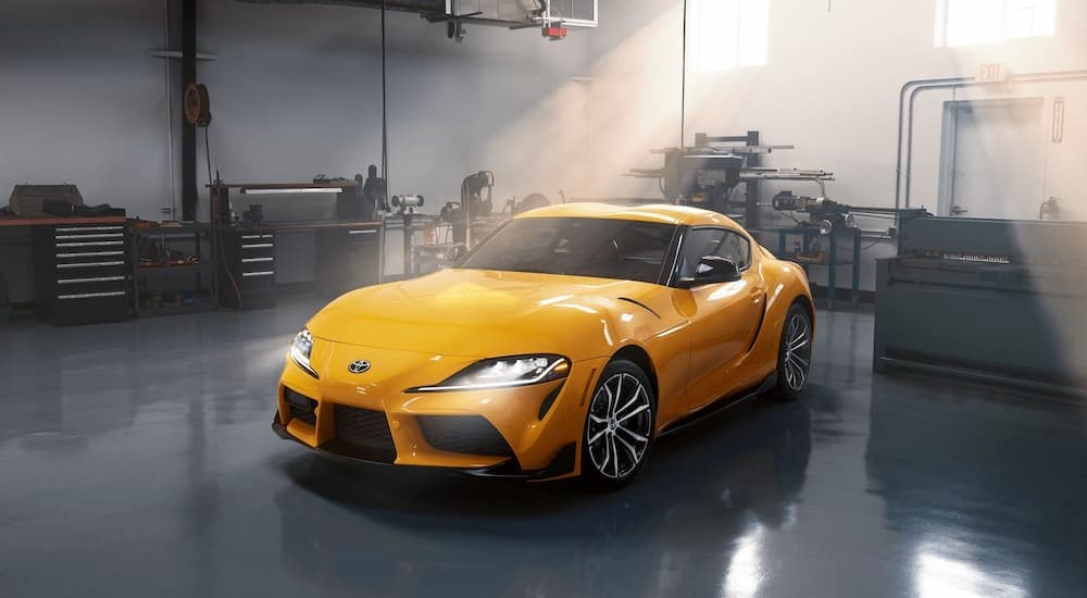 A yellow 2023 Toyota GR Supra is shown parked in a garage.