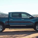 A black 2024 Chevy Silverado 1500 High Country is shown parked on a farm.